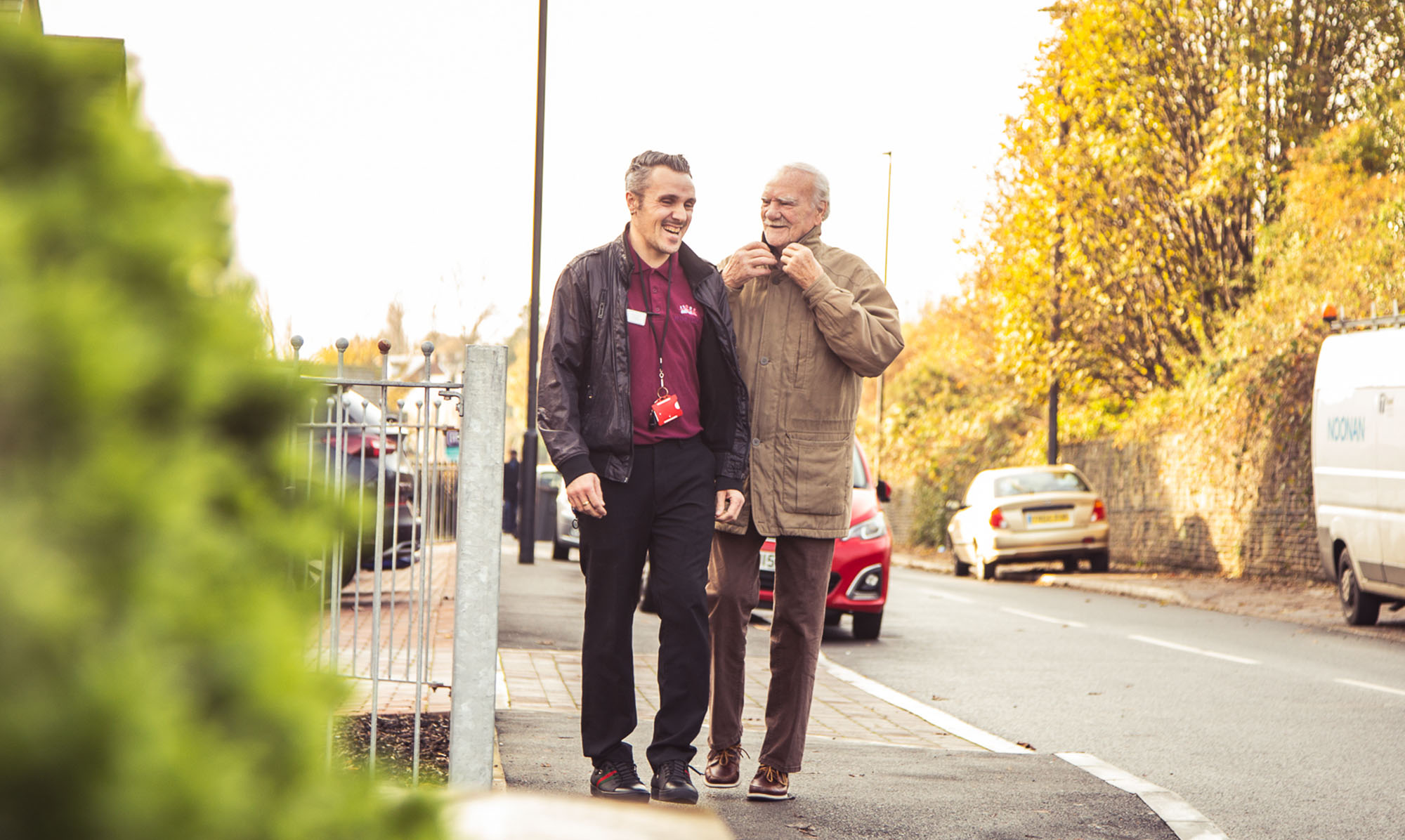 Carer walking with patient down a street.