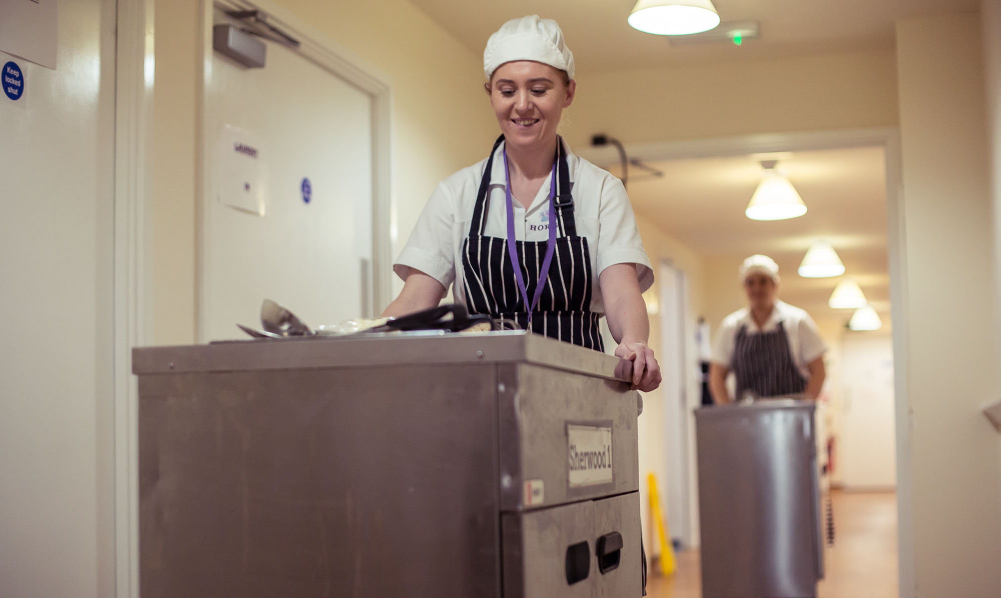 Chef pushing a trolley down a hallway