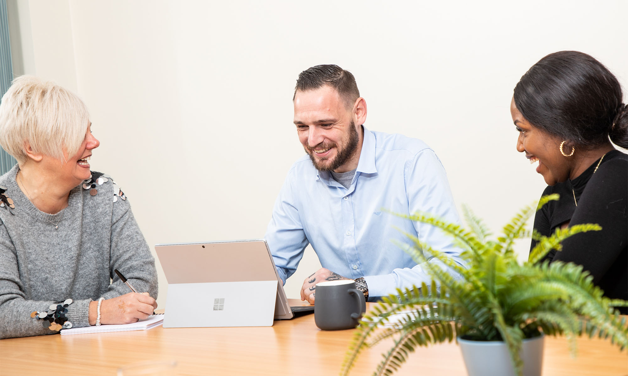 Jiggle colleagues in conversation, looking at laptop computer.