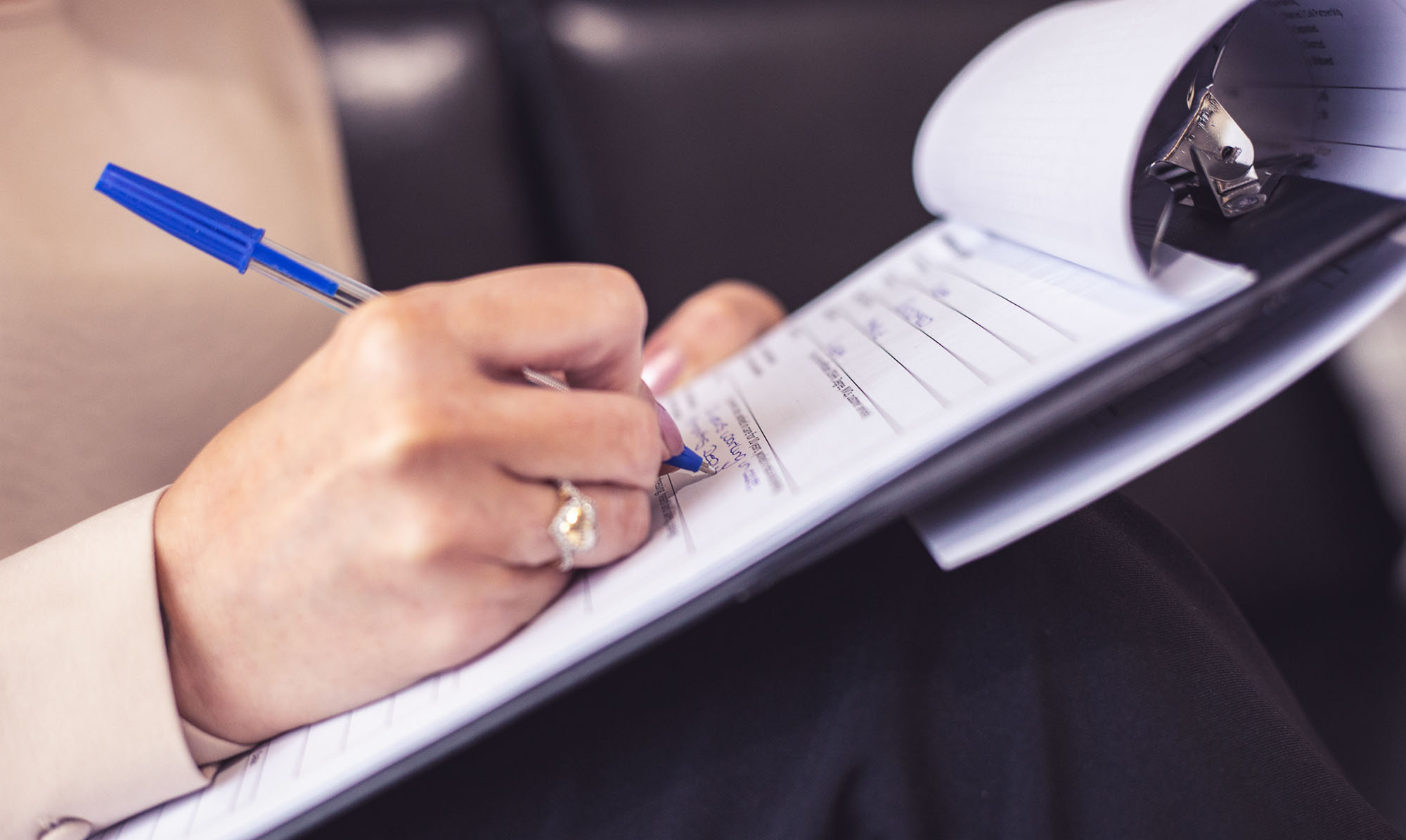 Close up image of person writing on clipboard